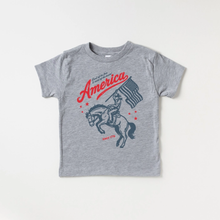 Load image into Gallery viewer, Gray t-shirt with a graphic of a cowboy, horse, American flag, and text on a white background.