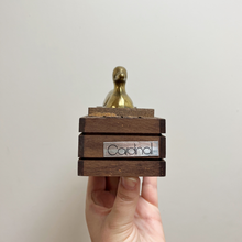 Load image into Gallery viewer, The original Cardnal sticker on the side of the domino box with the brass duck on top
