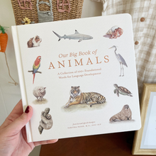 Load image into Gallery viewer, Book titled 'Our Big Book of Animals' held by a hand with a decorative background.