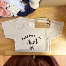 Load image into Gallery viewer, A light heather gray baby short-sleeve bodysuit with 'PASS ME TO MY Aunt' and a heart printed in black, displayed on a wooden surface with a 'Gracie Lou' brand tag attached.