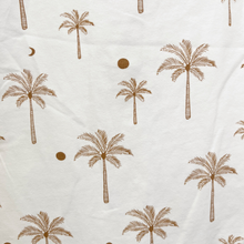 Load image into Gallery viewer, A close up picture of the cotton fabric that a baby boy jumpsuit is made from: white fabric with a brown palm tree and sun print pattern.