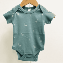 Load image into Gallery viewer, Teal baby onesie with small white golf cart and golf flag patterns on a wooden hanger against a light background