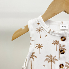 Load image into Gallery viewer, A close up detail of the collar of a baby boy romper in white with a brown palm tree pattern, hanging on a wooden hanger against a light gray background.