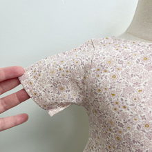 Load image into Gallery viewer, A close up of the sleeve detail of an organic cotton floral dress on a baby size mannequin in front of a white wall.