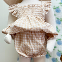 Load image into Gallery viewer, Baby mannequin wearing a checkered gingham outfit with a blurred floral background