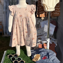 Load image into Gallery viewer, A baby mannequin wearing a dress with a summer pattern consisting of summer illustrations: crabs, scooters, beach chairs, waves, and more.