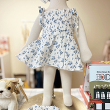 Load image into Gallery viewer, Mannequin wearing a white romper with blue floral pattern in a children's boutique setting.