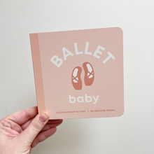 Load image into Gallery viewer, Hand holding a pink book titled 'Ballet Baby' with ballet shoes illustration on a light gray background