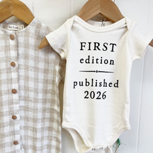 Load image into Gallery viewer, Baby onesie with 'First edition published 2026' text on a hanger with a shirt.