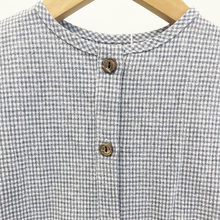 Load image into Gallery viewer, A close up of the button details of a blue gingham infant baby romper, hanging on a wooden hanger in front of a white background inside Gracie Lou.