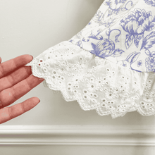 Load image into Gallery viewer, Hand holding the bottom of the dress to highlight the white eyelet lace trim on the blue floral and bunny dress.