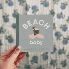 Load image into Gallery viewer, Hand holding a book titled 'Beach Baby' with a floral background