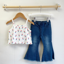 Load image into Gallery viewer, A picture showing an example of how to style the white pointelle baby top that comes as part of a shirt and shorts set that features a popsicle print, that is paired with denim bell bottoms.
