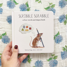 Load image into Gallery viewer, Book titled 'Scribble Scrabble' held by a hand on a floral background