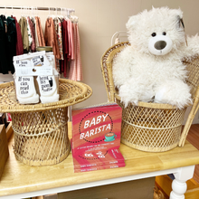 Load image into Gallery viewer, Baby Barista board book on display with baby socks and a white teddy bear in a children's store.