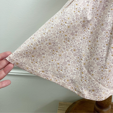 Load image into Gallery viewer, A close up of an organic cotton floral dress on a baby size mannequin in front of a white wall.
