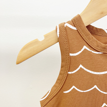 Load image into Gallery viewer, A close up of the sleeveless baby boy jumpsuit with a white wave pattern hanging on a wooden hanger against a plain light background.