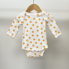 Load image into Gallery viewer, A baby long-sleeve bodysuit in white cotton pointelle fabric with an all-over orange pumpkin print, hanging on a wooden hanger against a neutral light gray background.