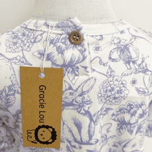 Load image into Gallery viewer, The picture shows the button closure at the back of the neck for the floral and bunny pattern dress and a 'Gracie Lou' tag.