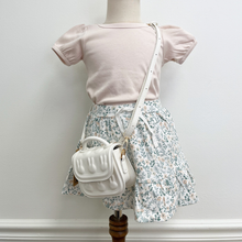 Load image into Gallery viewer, Shell colored A-line tee shirt paired with a floral skirt and a white crossbody on a mannequin.