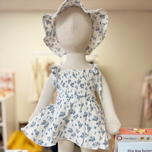 Load image into Gallery viewer, A baby size mannequin wearing a floral romper and matching hat with a blurred background