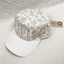 Load image into Gallery viewer, Floral-patterned cap with tassels on a light gray background