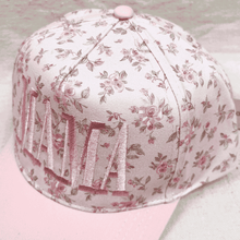 Load image into Gallery viewer, Floral-patterned cap with pink button on a light background