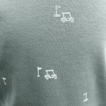 Load image into Gallery viewer, Teal shirt with white golf cart and flag designs on a gray background