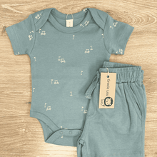 Load image into Gallery viewer, Teal baby onesie and shorts set with musical note pattern on a wooden surface, Grade Lou brand visible.