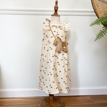 Load image into Gallery viewer, A toddler size muslin dress with a horse print on a cream dress styled on a mannequin in front of a white wall.