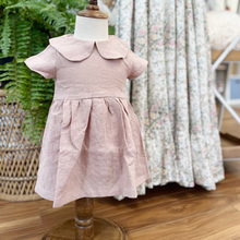Load image into Gallery viewer, A dusty pink, linen children's dress on a baby size mannequin in front of a green fern on a wicker peacock chair. This item is featured inside Gracie Lou, a children's boutique with locations in Hollidaysburg &amp; Bedford, PA.