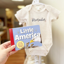 Load image into Gallery viewer, Baby onesie with 'firecracker' text and a book titled 'Little America' held by a hand.