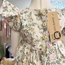 Load image into Gallery viewer, A close up of the back of a floral baby romper on an infant mannequin with a 'Gracie Lou' tag in the childrens boutique in Bedford, PA