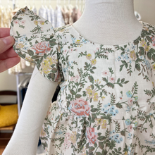 Load image into Gallery viewer, A close up of the sleeve on a floral patterned baby romper on a mannequin with a blurred background inside Gracie Lou