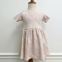 Load image into Gallery viewer, An organic cotton floral dress on a baby size mannequin in front of a white wall.