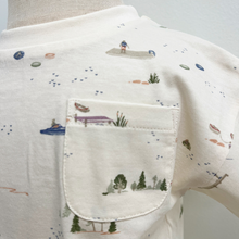 Load image into Gallery viewer, The pocket detail of a short-sleeve toddler t-shirt in cream with a delicate, all-over watercolor-style print of boats, sailboats, ships, and small trees. The shirt features a classic crew neck and a left chest pocket, styled on a mannequin.