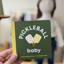 Load image into Gallery viewer, Book titled 'Pickleball Baby' held by a person with a blurred background