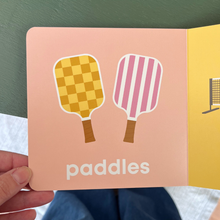 Load image into Gallery viewer, A Children's book (Pickleball) page with illustrations of paddles and the word 'paddles' on a pink background 
