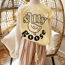 Load image into Gallery viewer, A toddler mannequin standing in front of an egg chair wearing a Silly Goose tee shirt and striped pants