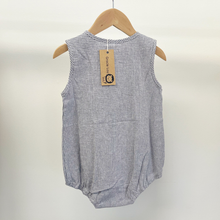 Load image into Gallery viewer, An infant baby romper with front buttons, hanging on a wooden hanger in front of a white background inside a children's boutique in Hollidaysburg ,PA.