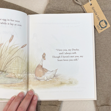 Load image into Gallery viewer, An open children's book, I've Loved You From The Start, showing a watercolor illustration of a duck and a printed quote, held by a hand over a beige knit sweater with a branded Gracie Lou tag attached.