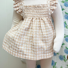 Load image into Gallery viewer, Checkered gingham top and bottom worn by a baby mannequin with a floral patterned background